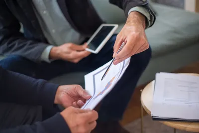 Close-up of two business professionals discussing documents in a meeting.